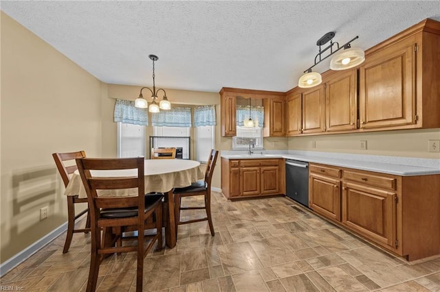 kitchen featuring sink, hanging light fixtures, stainless steel dishwasher, a notable chandelier, and a textured ceiling