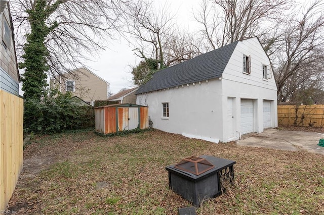 view of home's exterior featuring a garage, an outdoor fire pit, and a storage unit