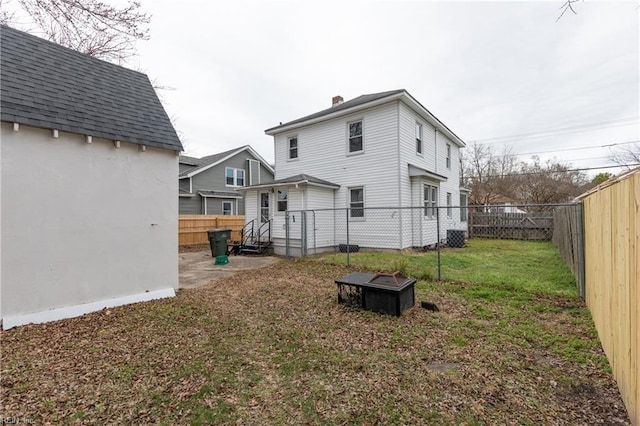 back of house featuring a yard and a fire pit