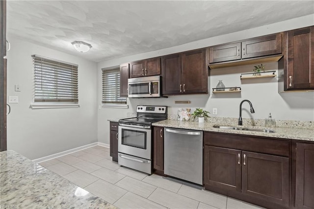 kitchen featuring appliances with stainless steel finishes, sink, light stone counters, and dark brown cabinetry