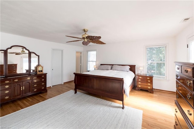 bedroom featuring ceiling fan, multiple windows, and light hardwood / wood-style flooring