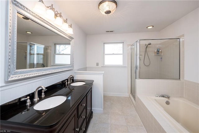 bathroom featuring a healthy amount of sunlight, independent shower and bath, and vanity