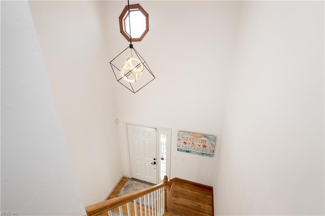 staircase with a towering ceiling and hardwood / wood-style floors