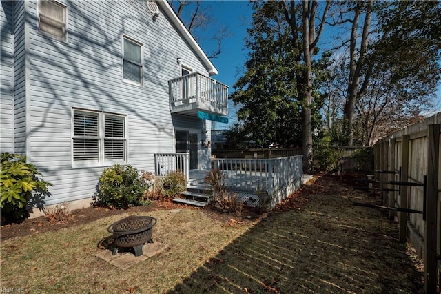 view of yard featuring a wooden deck, a balcony, and an outdoor fire pit