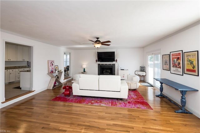 living room featuring hardwood / wood-style flooring, ornamental molding, and ceiling fan