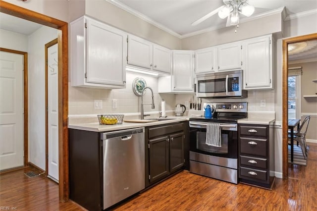 kitchen featuring sink, white cabinetry, crown molding, appliances with stainless steel finishes, and dark hardwood / wood-style floors