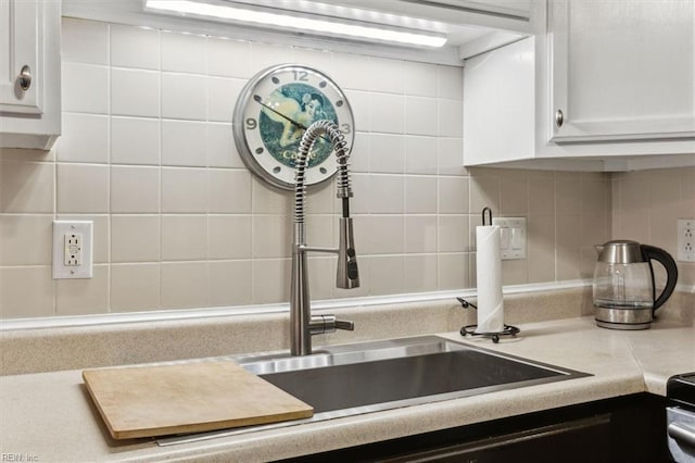 interior details with backsplash, sink, and white cabinets