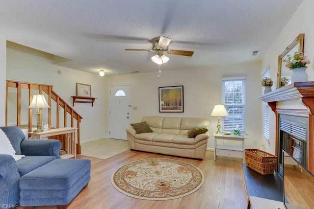 living room featuring ceiling fan, hardwood / wood-style flooring, and a textured ceiling