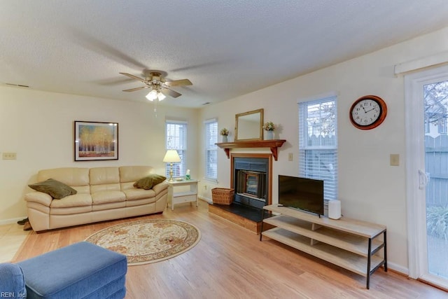 living room with hardwood / wood-style flooring, ceiling fan, and a textured ceiling