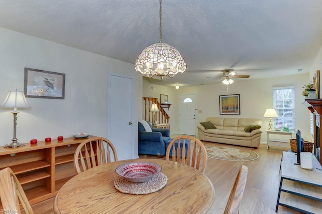 dining space with ceiling fan, a textured ceiling, and light wood-type flooring