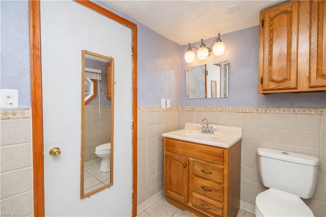 bathroom featuring tile patterned flooring, vanity, tile walls, and toilet