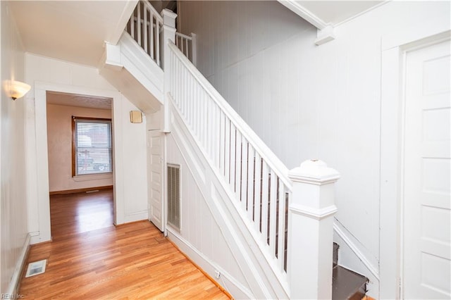 staircase with hardwood / wood-style flooring and ornamental molding