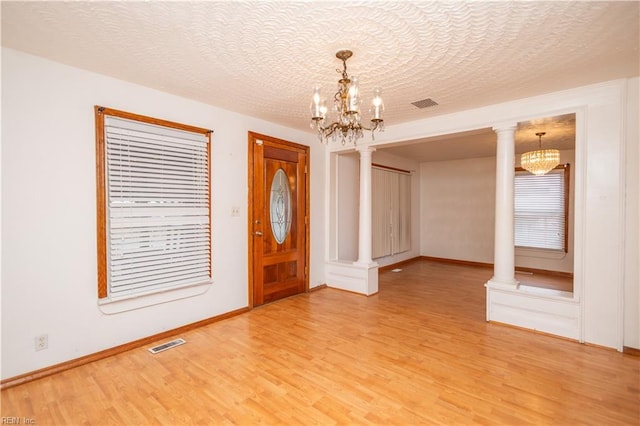 entryway featuring an inviting chandelier, hardwood / wood-style flooring, and decorative columns