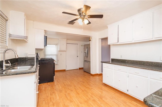 kitchen featuring stainless steel refrigerator with ice dispenser, black gas stove, sink, and white cabinets