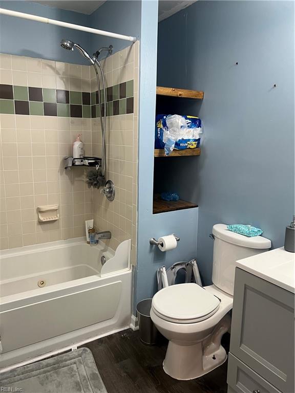 full bathroom with wood-type flooring, toilet, tiled shower / bath combo, and vanity