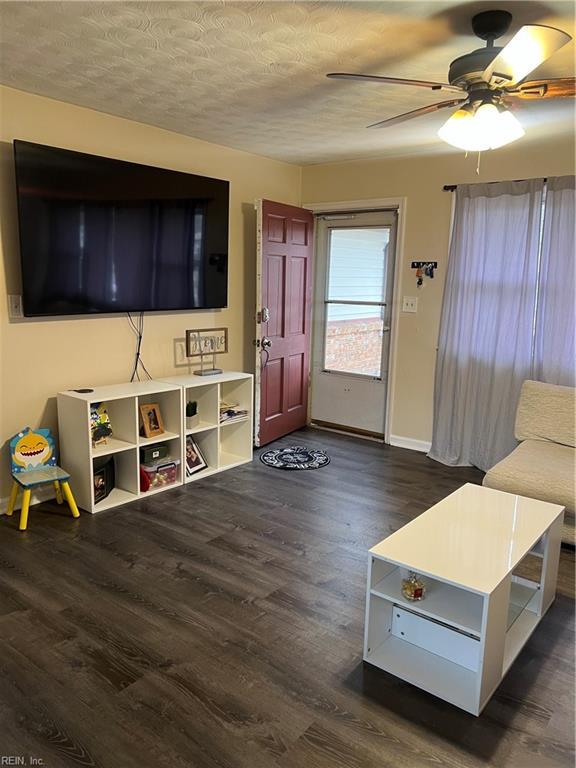 living room featuring ceiling fan, dark hardwood / wood-style floors, and a textured ceiling