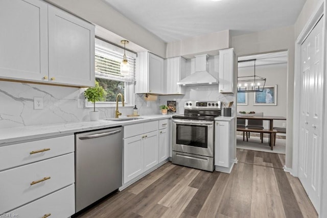 kitchen featuring wall chimney exhaust hood, appliances with stainless steel finishes, sink, and white cabinets