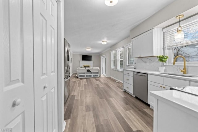 kitchen featuring hanging light fixtures, dishwasher, sink, and white cabinets