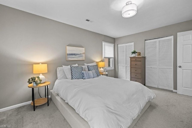 bedroom featuring light colored carpet and two closets