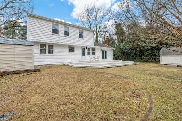 rear view of property with a storage unit, a yard, and a deck