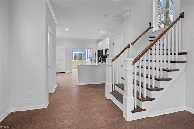 stairs featuring hardwood / wood-style flooring, crown molding, and sink