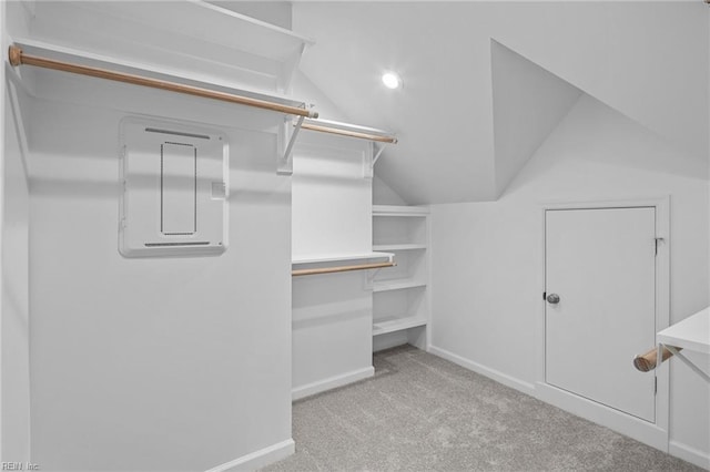 walk in closet with light carpet, lofted ceiling, and electric panel