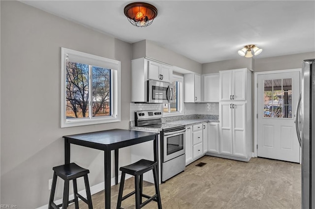 kitchen featuring backsplash, appliances with stainless steel finishes, and white cabinets