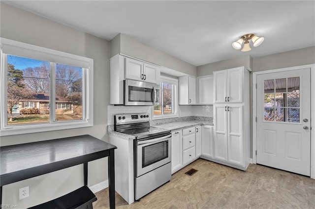 kitchen featuring tasteful backsplash, appliances with stainless steel finishes, and white cabinets