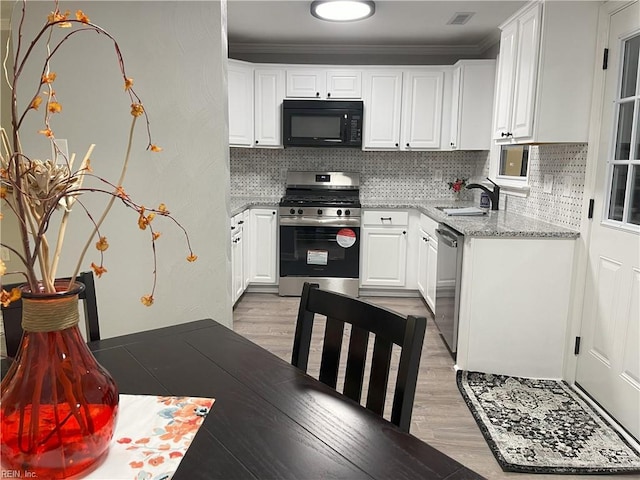 kitchen featuring appliances with stainless steel finishes, white cabinetry, sink, light hardwood / wood-style floors, and light stone countertops