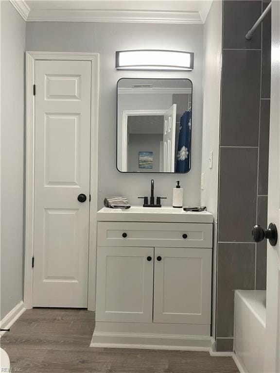 bathroom featuring crown molding, tub / shower combination, hardwood / wood-style floors, and vanity