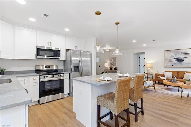 kitchen with pendant lighting, white cabinetry, stainless steel appliances, and a center island