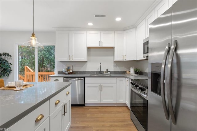 kitchen featuring sink, white cabinetry, hanging light fixtures, stainless steel appliances, and light stone countertops