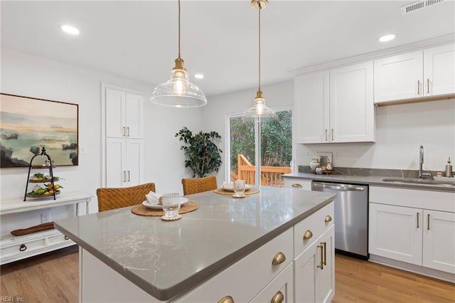 kitchen featuring dishwasher, sink, a kitchen island, and white cabinets