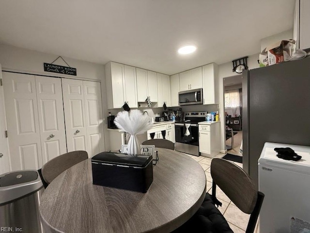 kitchen with stainless steel appliances, light tile patterned floors, and white cabinets