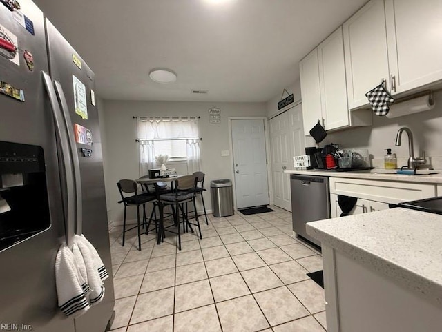 kitchen with white cabinetry, appliances with stainless steel finishes, sink, and light tile patterned floors