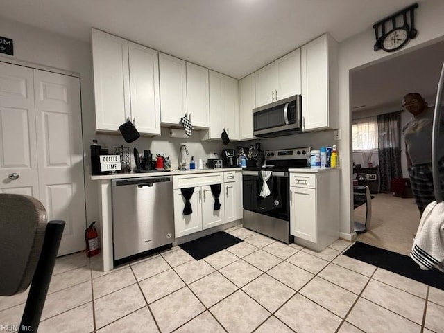 kitchen with stainless steel appliances, white cabinets, and light tile patterned flooring