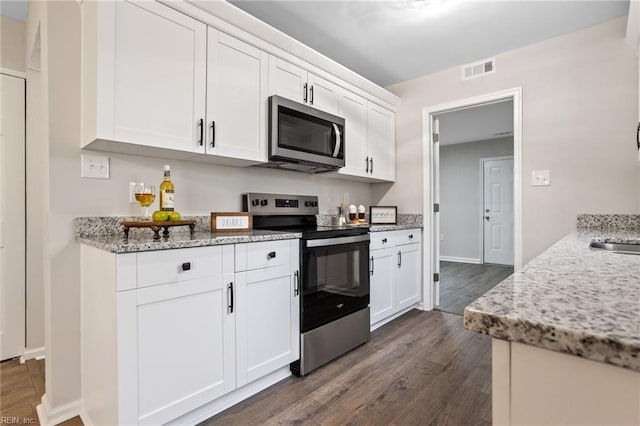 kitchen featuring white cabinetry, appliances with stainless steel finishes, dark hardwood / wood-style floors, and light stone counters