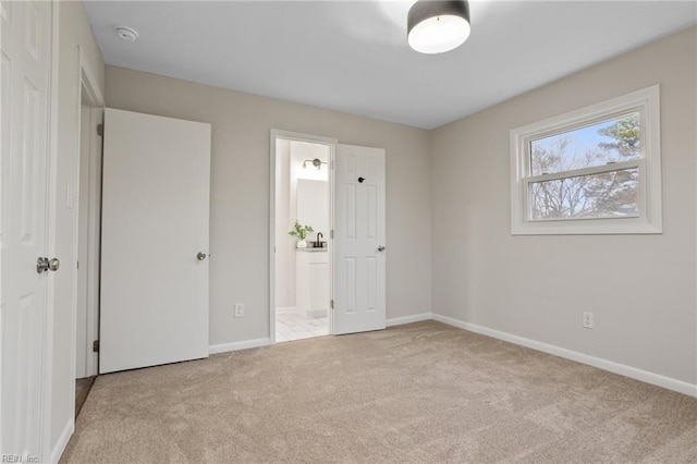 unfurnished bedroom featuring light carpet and ensuite bath