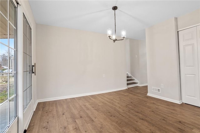 unfurnished dining area with wood-type flooring and a chandelier