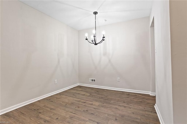 unfurnished dining area featuring an inviting chandelier and dark hardwood / wood-style flooring