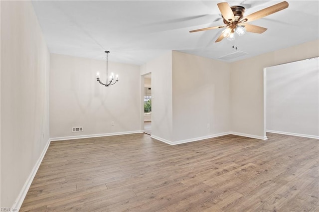 spare room with ceiling fan with notable chandelier and light wood-type flooring