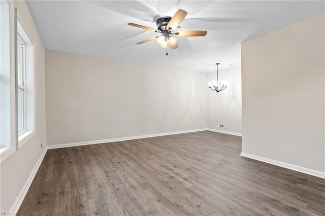 spare room featuring dark hardwood / wood-style floors and ceiling fan with notable chandelier