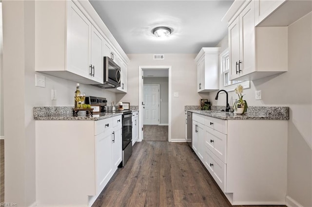 kitchen featuring dark wood-type flooring, sink, stainless steel appliances, light stone countertops, and white cabinets