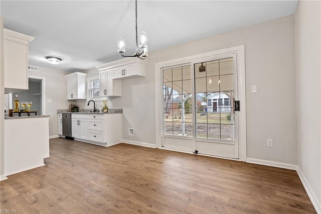 kitchen with sink, light hardwood / wood-style flooring, stainless steel dishwasher, light stone countertops, and white cabinets