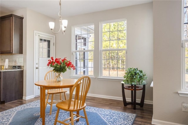 dining space with dark wood-type flooring, plenty of natural light, and a chandelier