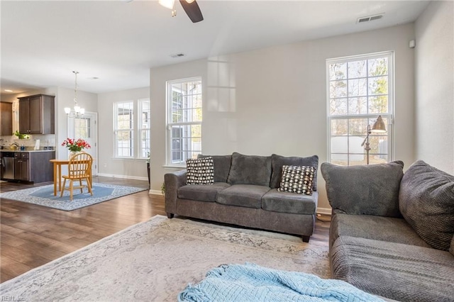 living room featuring sink, ceiling fan with notable chandelier, wood-type flooring, and plenty of natural light