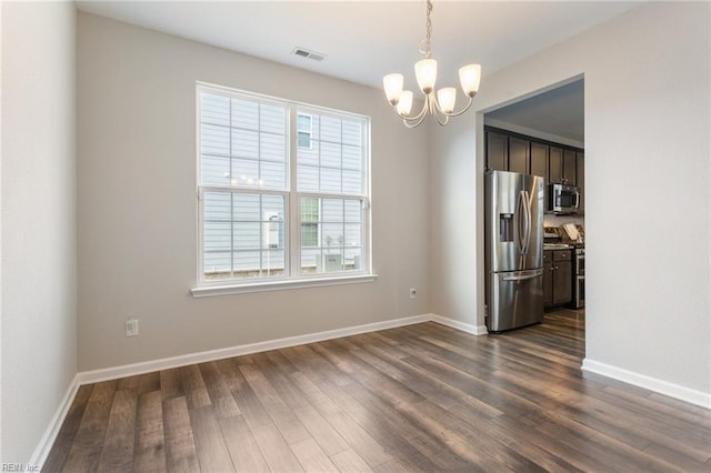 unfurnished dining area featuring dark wood-type flooring and a chandelier