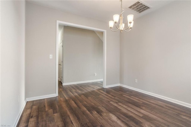 spare room with dark hardwood / wood-style flooring and an inviting chandelier