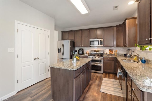 kitchen featuring sink, dark wood-type flooring, appliances with stainless steel finishes, tasteful backsplash, and a kitchen island