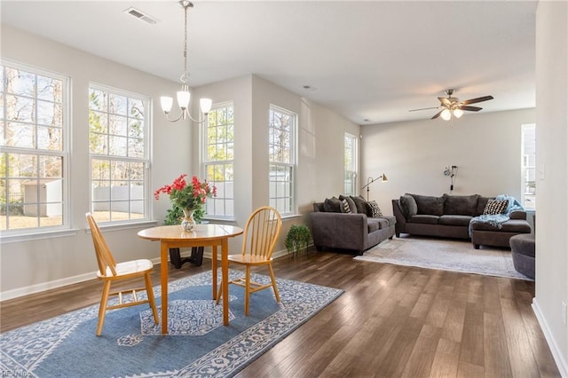 dining room featuring ceiling fan with notable chandelier and dark hardwood / wood-style flooring